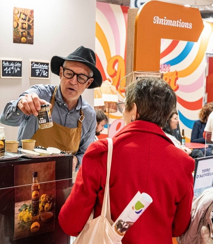 exposant qui échange avec une visiteur et lui parle d'un produit