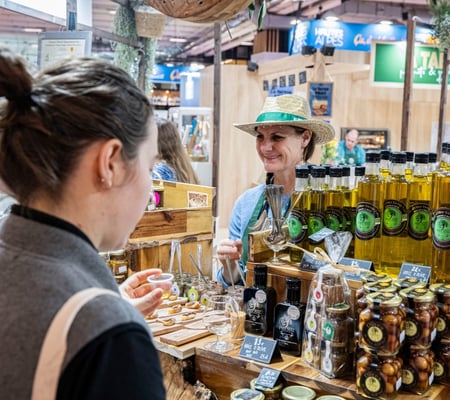 exposante souriante qui offre des échantillons à une visiteur