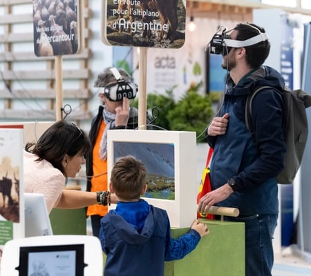 visiteur testant le casque à réalité virtuelle au salon de l'agriculture, avec un enfant et une femme qui lui montre un écran avec des informations