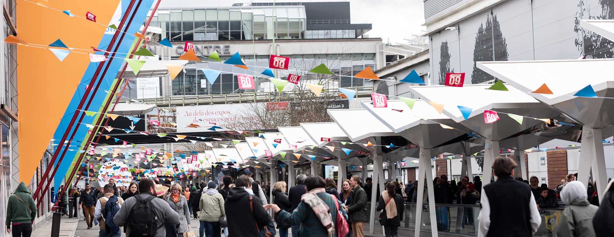Visiteurs à l'extérieur sous les guirlandes des 60 ans du salon