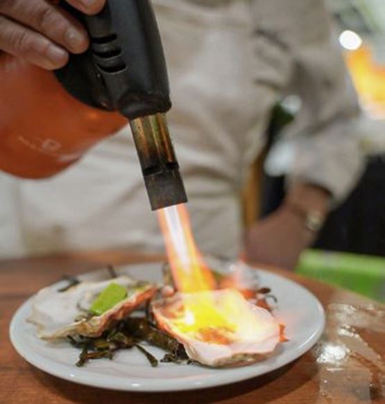 chef en train de flamber une huitre